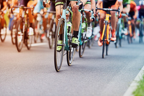 close up image of lots of cyclists legs and their colourful bikes during a cycling race close up image of lots of cyclists legs and their colourful bikes during a cycling race
